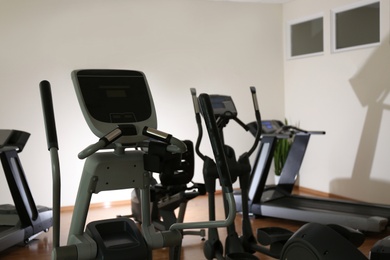 Photo of Elliptical trainer and treadmills in gym. Modern sport equipment