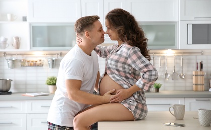 Photo of Pregnant woman with her husband in kitchen. Happy young family