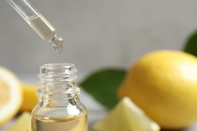 Photo of Citrus essential oil dripping from pipette into bottle, closeup. Space for text