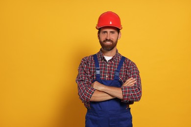 Photo of Professional builder in uniform on yellow background
