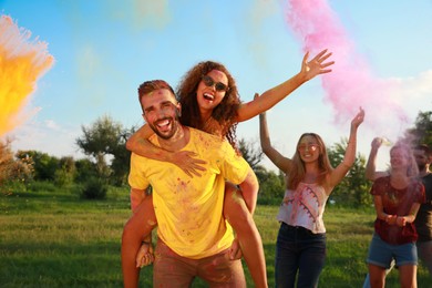 Photo of Happy couple covered with colorful powder dyes outdoors. Holi festival celebration