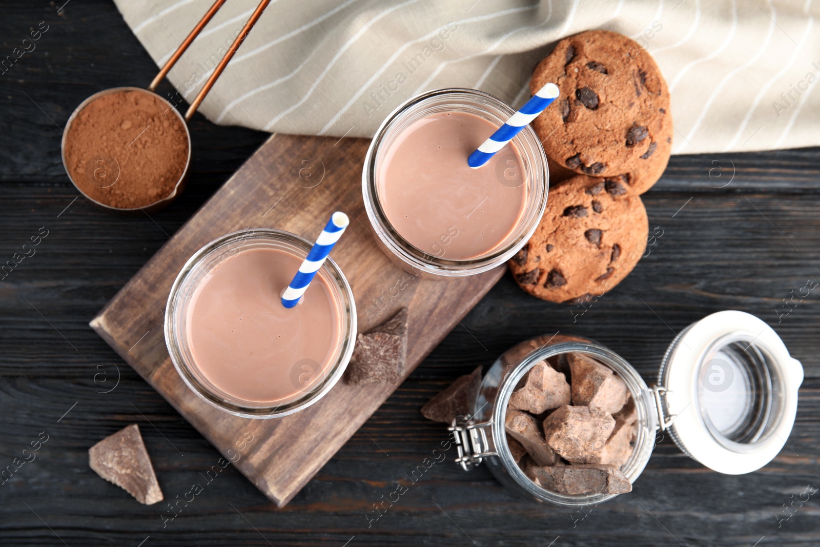 Photo of Flat lay composition with jars of tasty chocolate milk on wooden background. Dairy drink