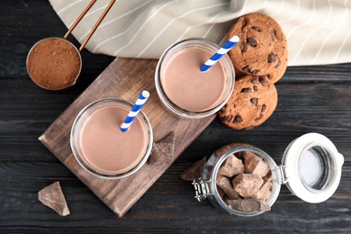 Flat lay composition with jars of tasty chocolate milk on wooden background. Dairy drink