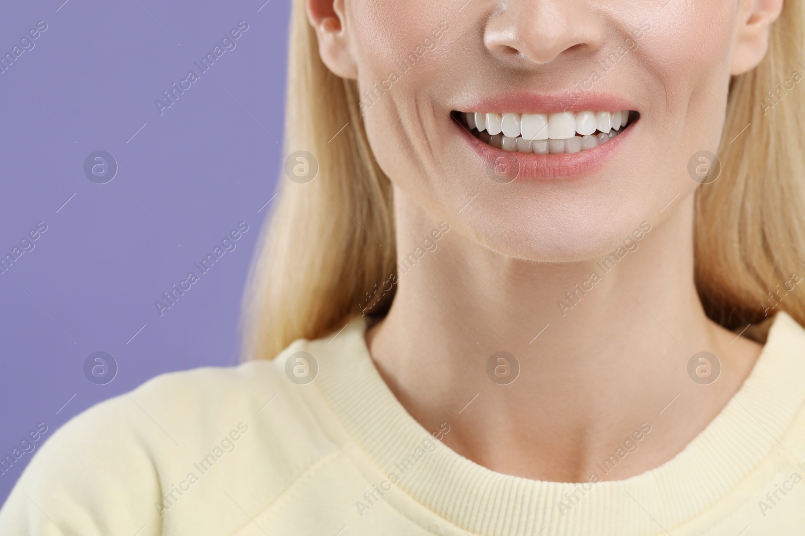 Photo of Woman with clean teeth smiling on violet background, closeup