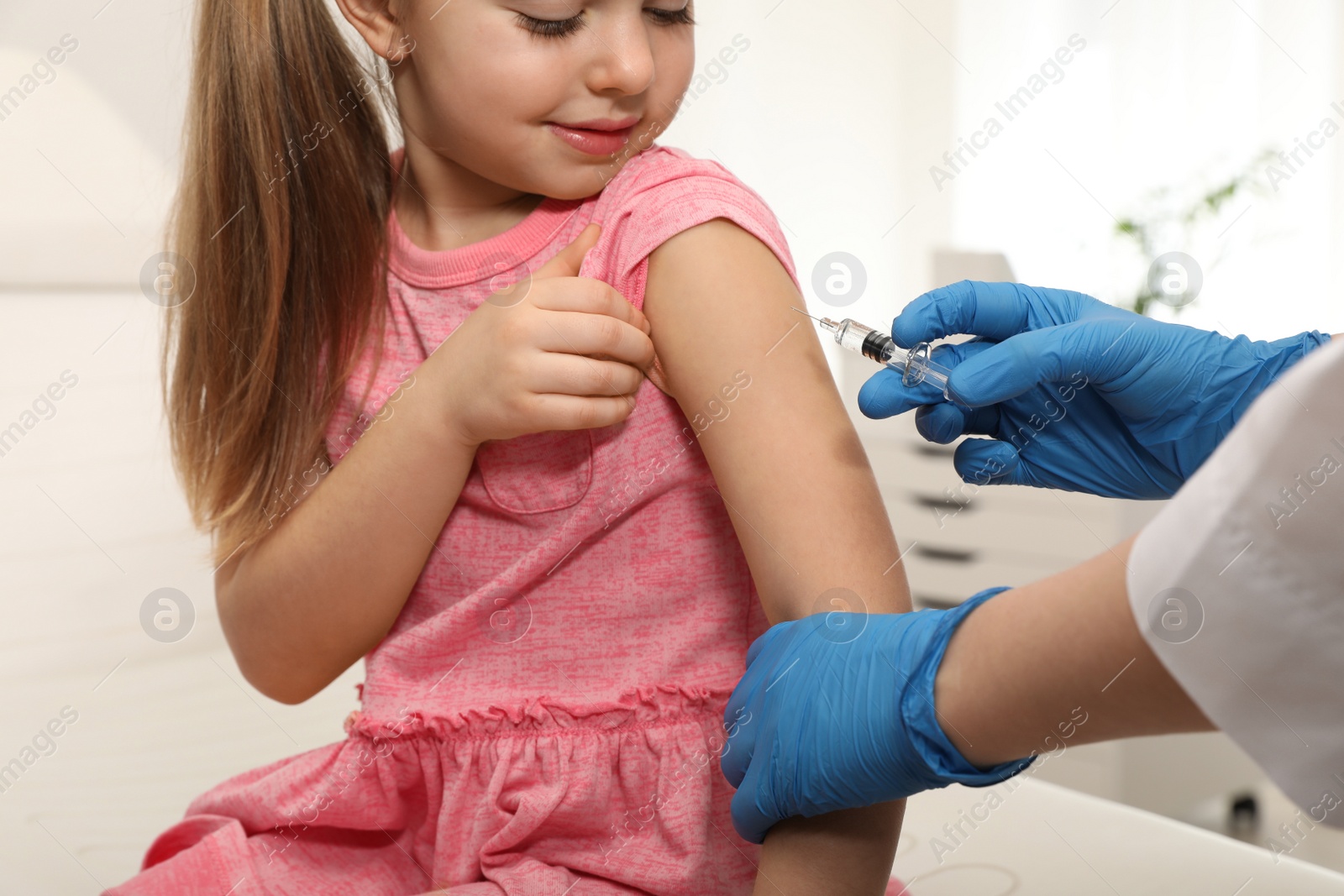 Photo of Doctor giving injection to little girl in hospital. Immunization concept