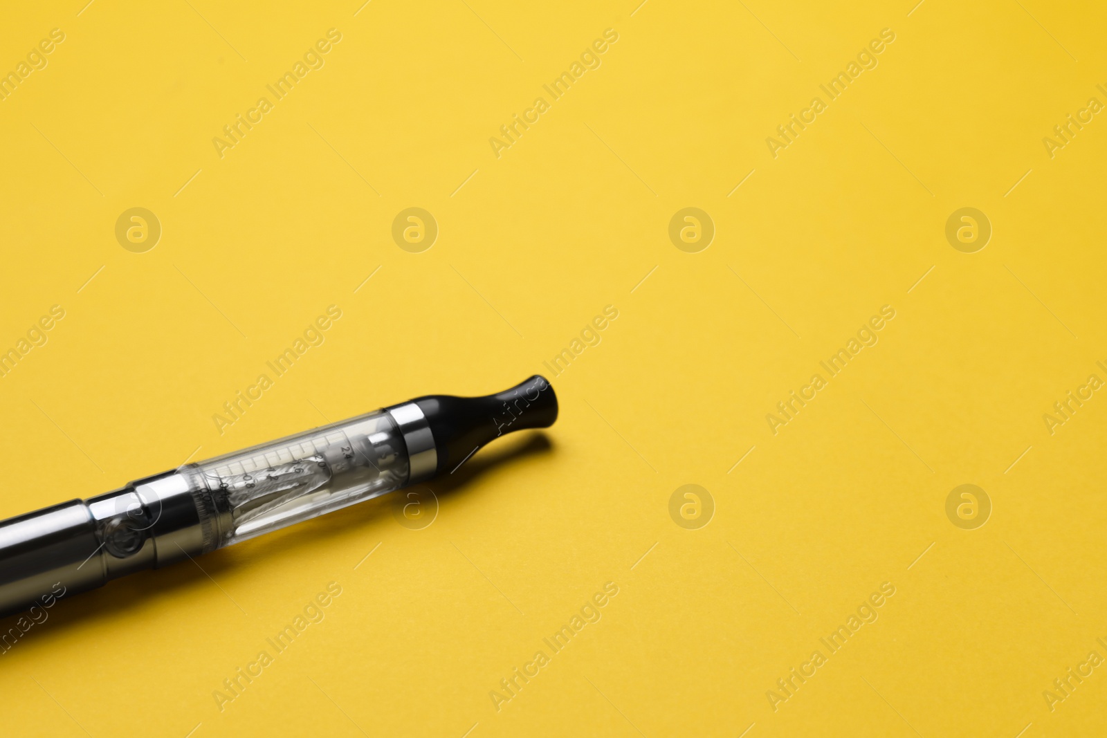 Photo of Electronic cigarette on yellow background, closeup. Space for text