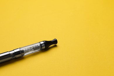 Electronic cigarette on yellow background, closeup. Space for text