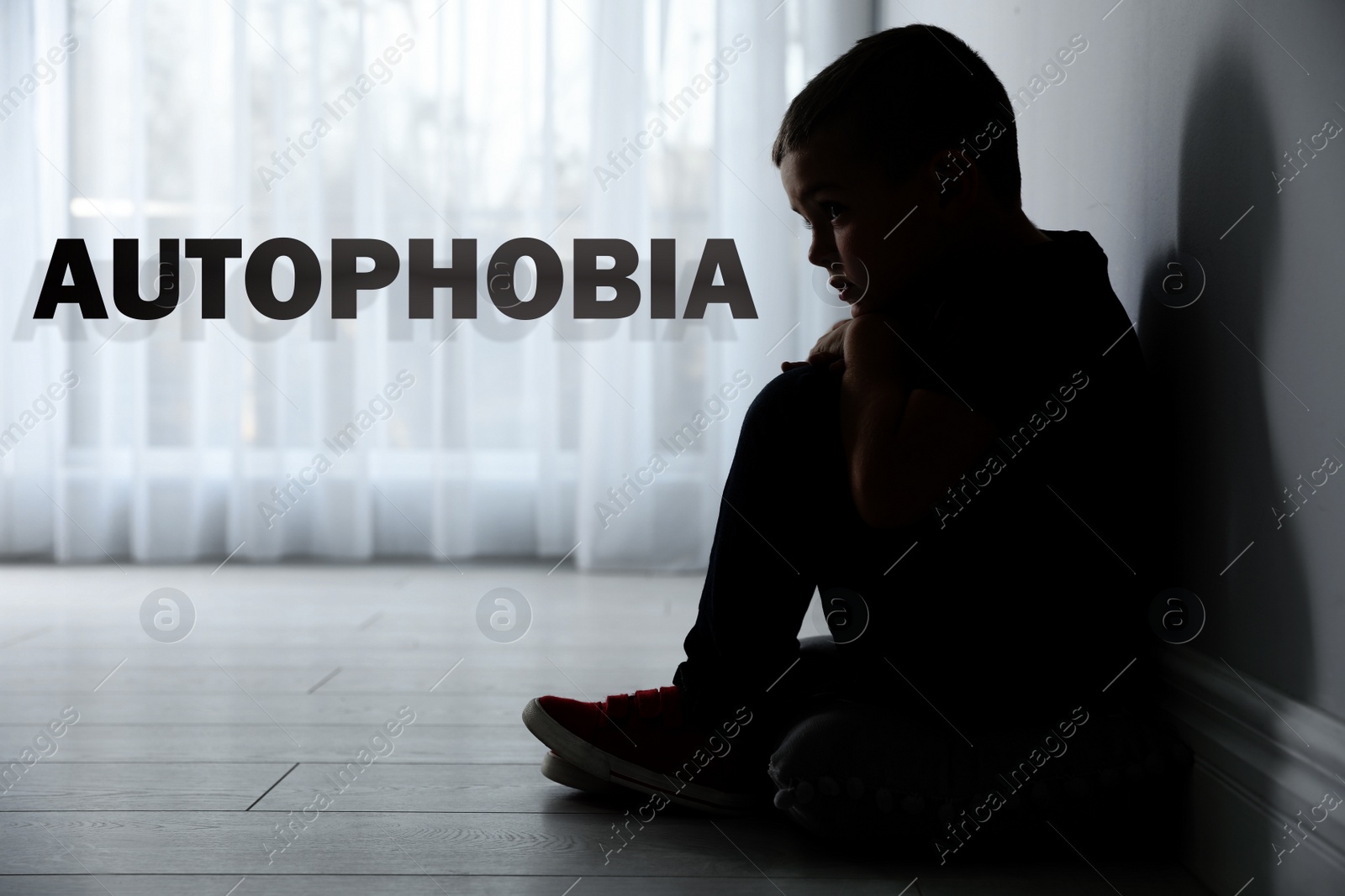 Image of Sad little boy sitting alone near wall at home. Autophobia - fear of isolation