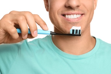 Man holding toothbrush with paste on white background, closeup