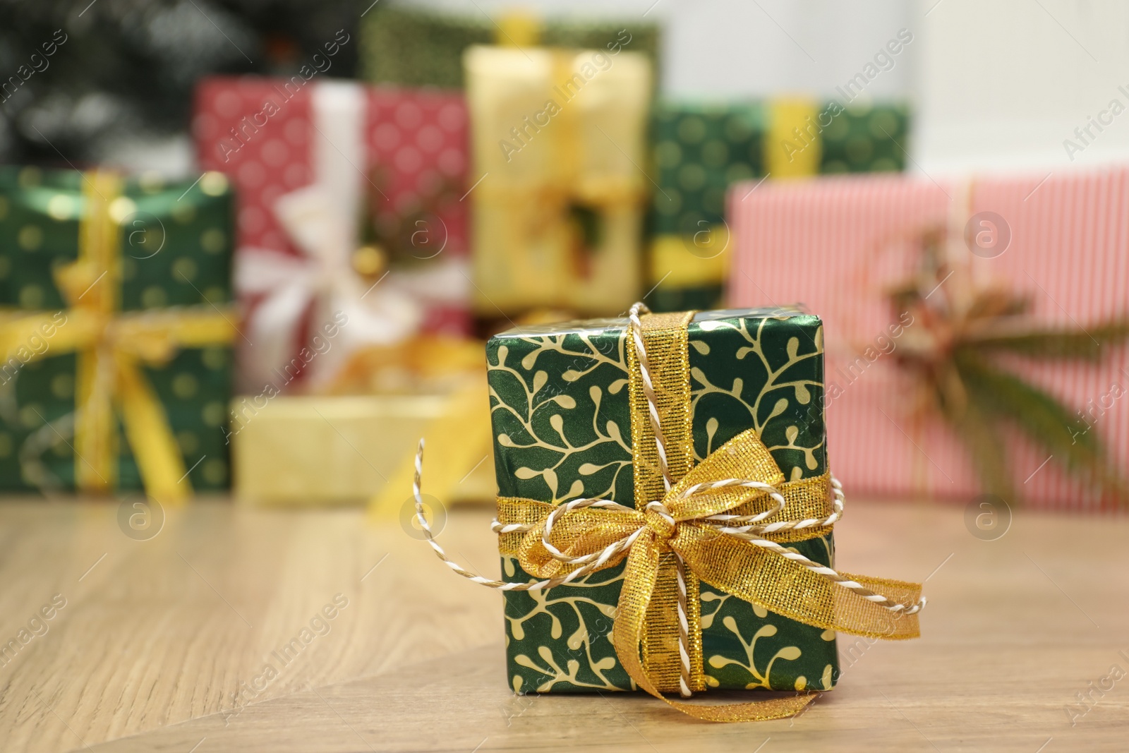 Photo of Beautiful Christmas gift and blurred pile of presents on background. Space for text