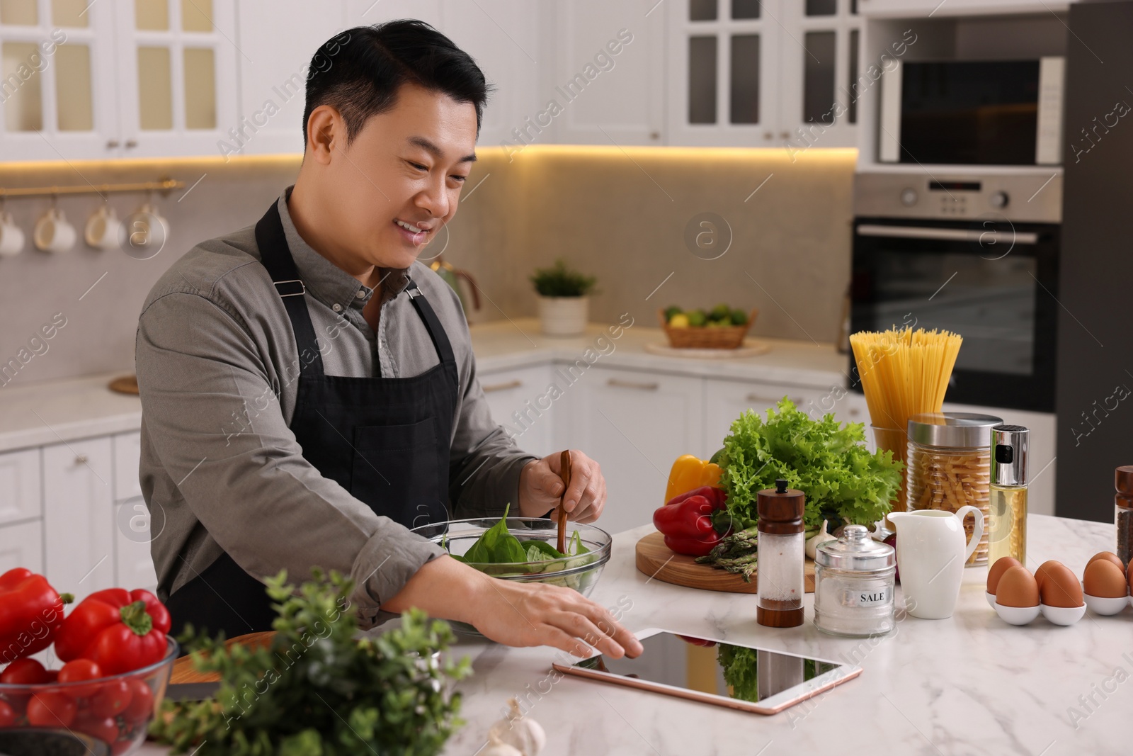 Photo of Man using tablet while cooking in kitchen