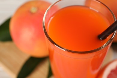 Photo of Tasty grapefruit juice in glass and fresh fruits on table, closeup. Space for text