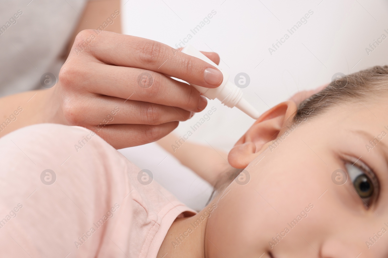 Photo of Mother dripping medication into daughter's ear, closeup