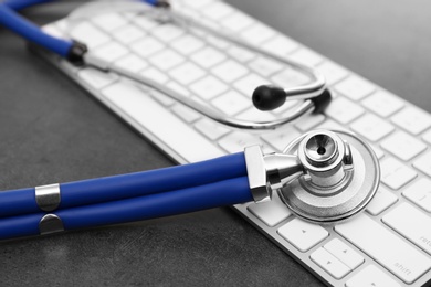 Photo of Modern keyboard and stethoscope on table. Technical support concept