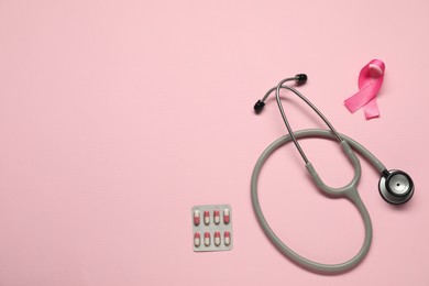 Breast cancer awareness. Pink ribbon, stethoscope and pills on color background, flat lay. Space for text