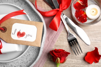 Photo of Beautiful place setting and tag with phrase I Love You  on wooden table, flat lay. Valentine's day romantic dinner
