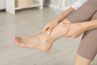 Photo of Woman rubbing sore leg at home, closeup