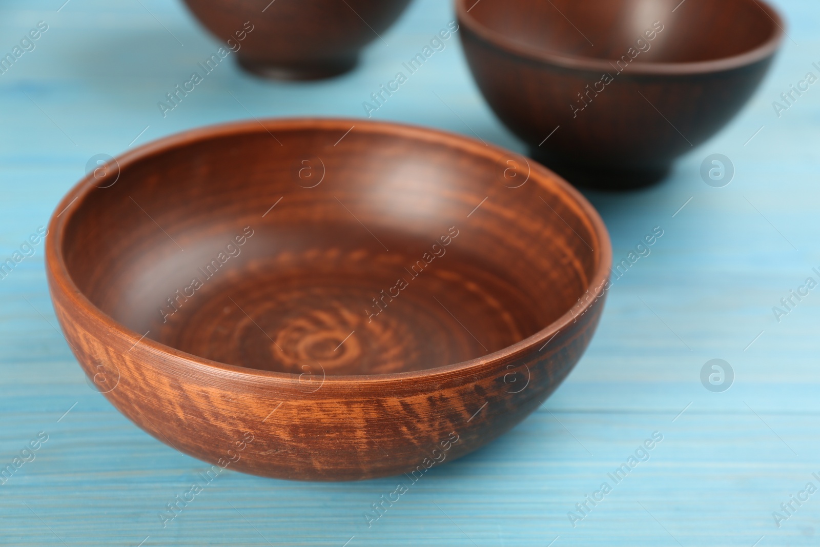 Photo of Clay bowl on light blue wooden table, closeup