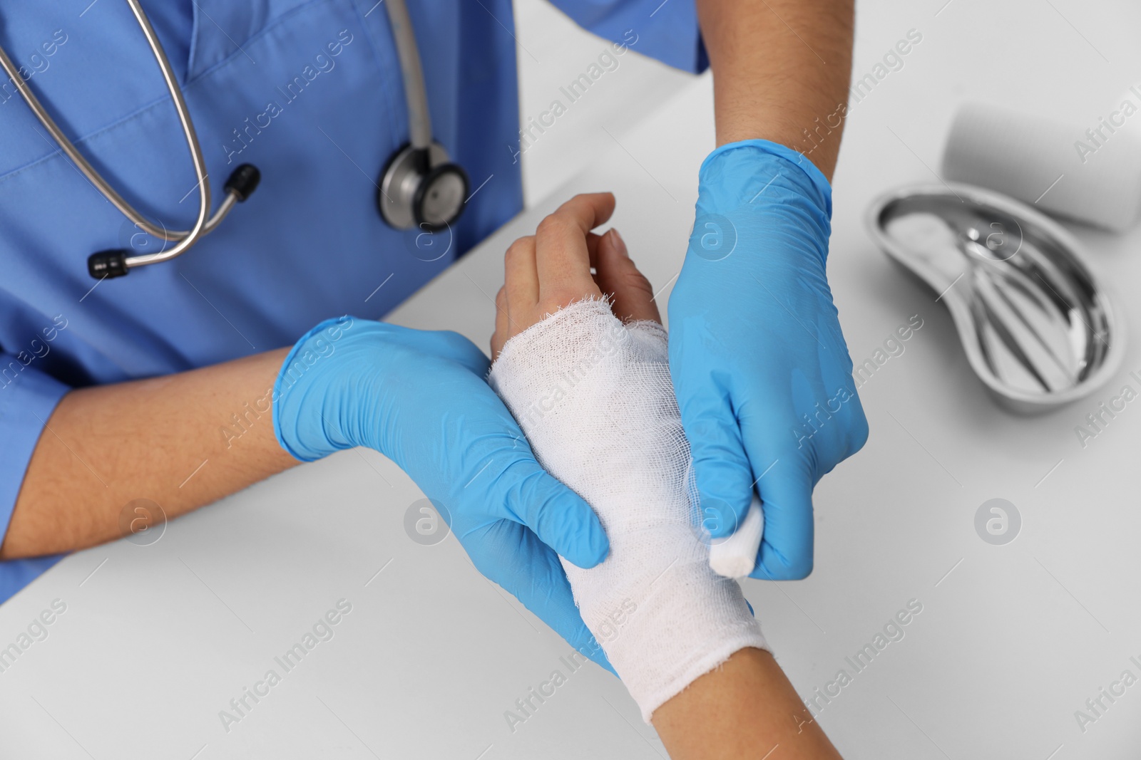 Photo of Doctor bandaging patient's burned hand at table, closeup