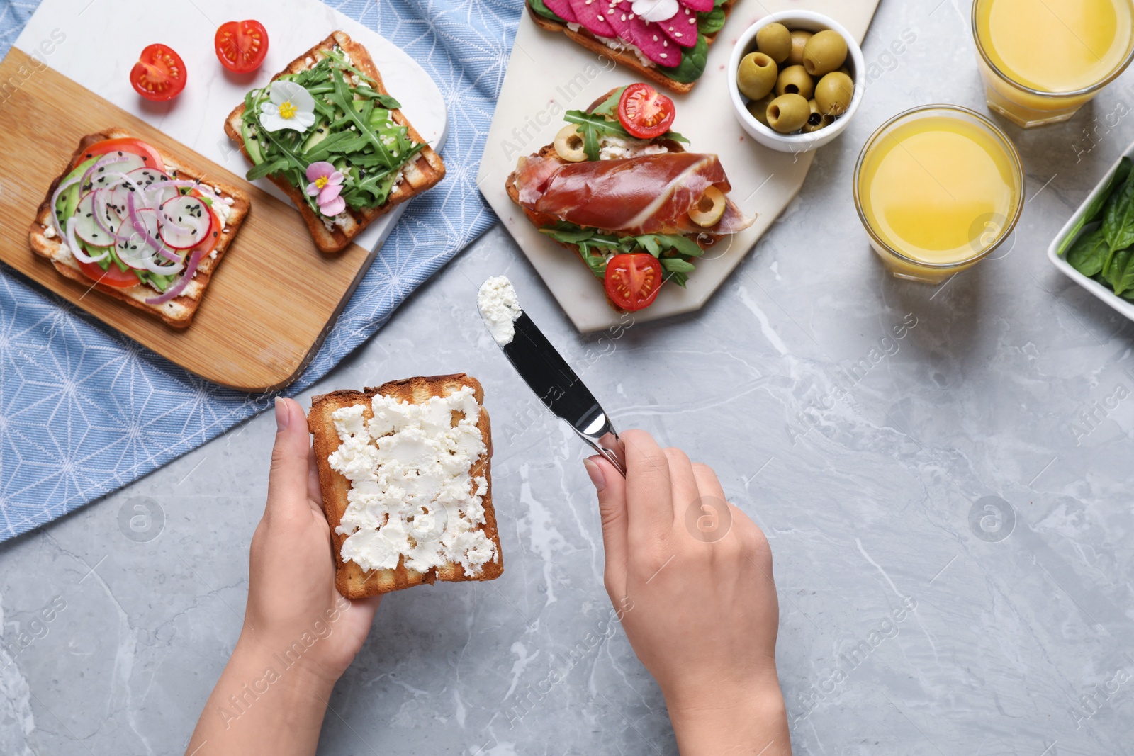 Photo of Woman cooking sandwich at light marble table, top view