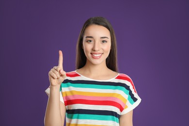 Photo of Woman showing number one with her hand on purple background