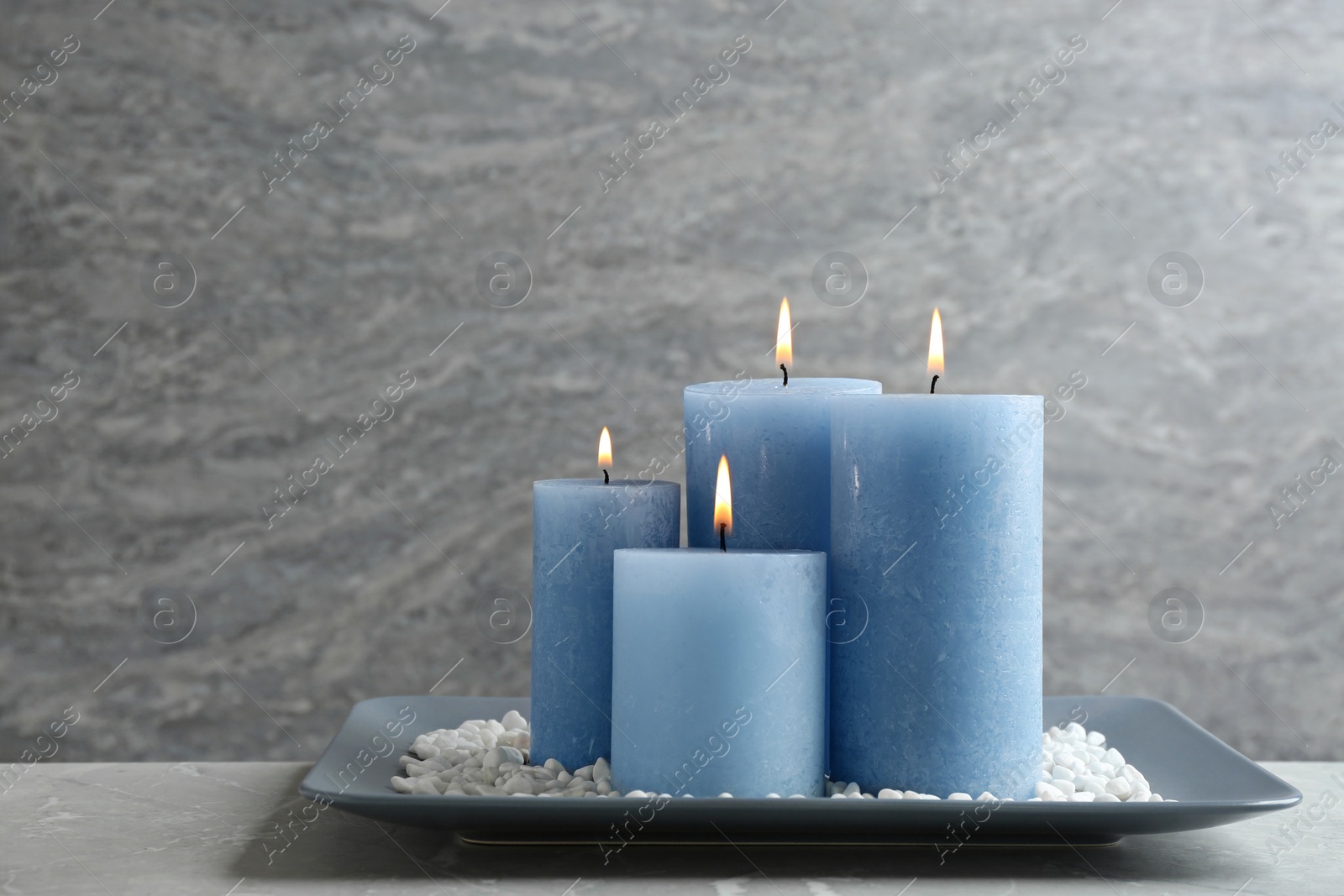 Photo of Plate with burning candles and rocks on table, space for text