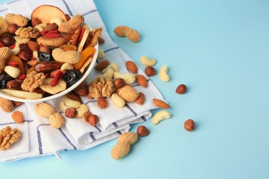 Photo of Bowl with mixed dried fruits and nuts on light blue background, space for text