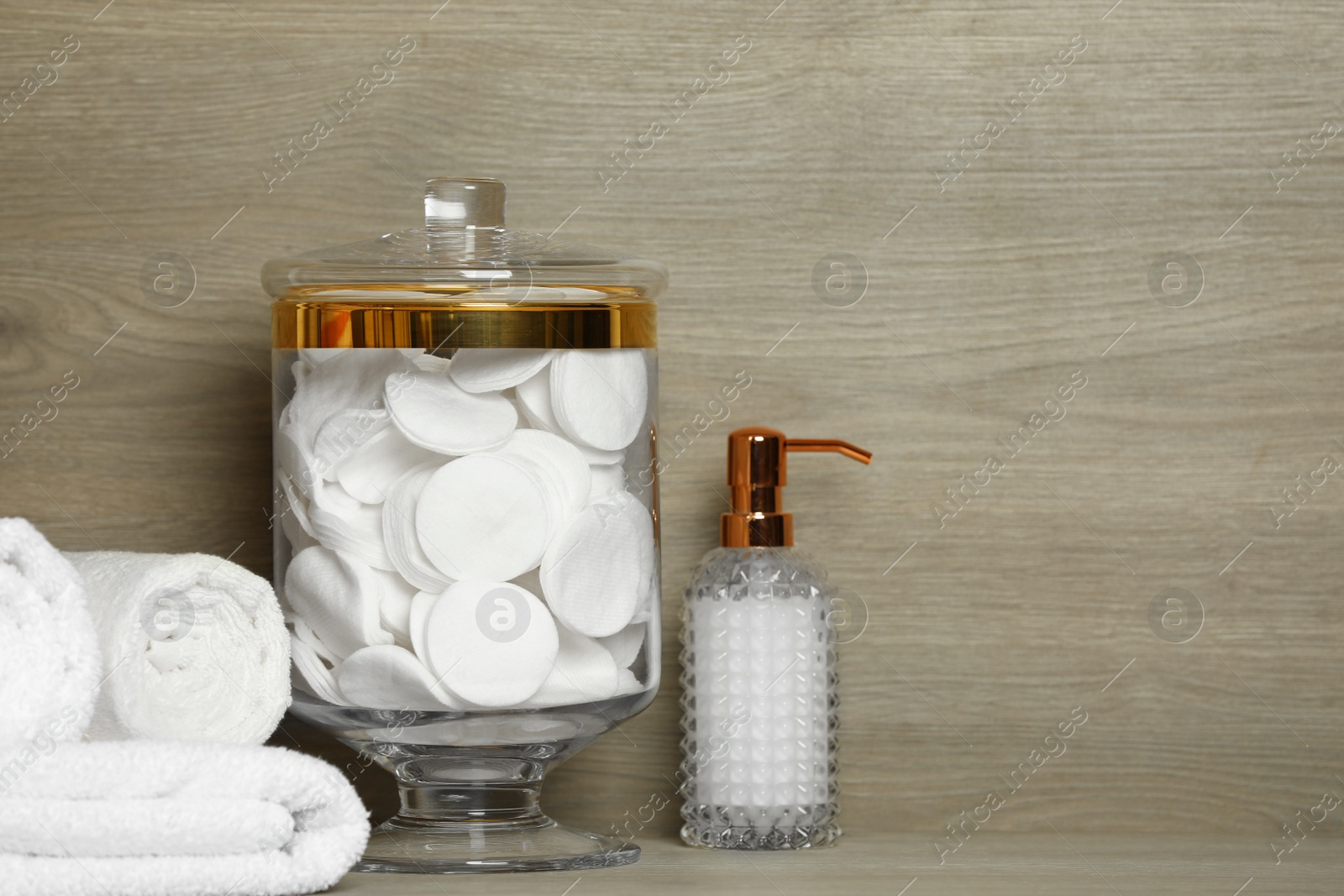 Photo of Composition of glass jar with cotton pads on table near wooden wall. Space for text