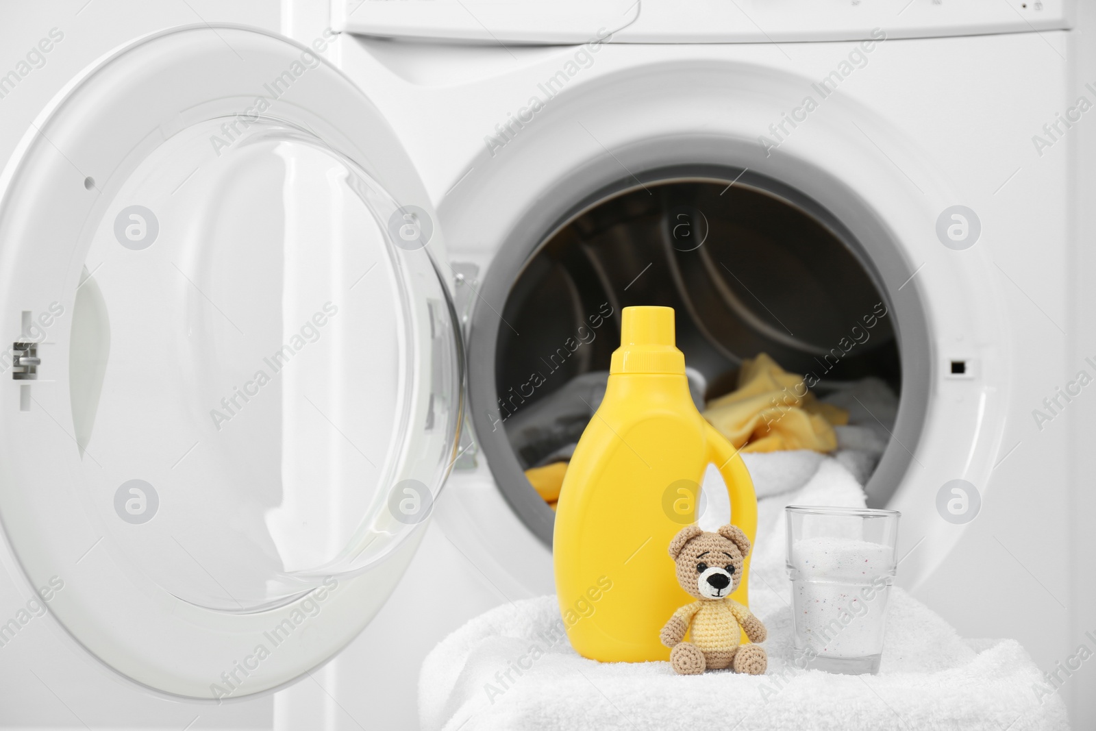 Photo of Bottle of detergent and children's toy near washing machine