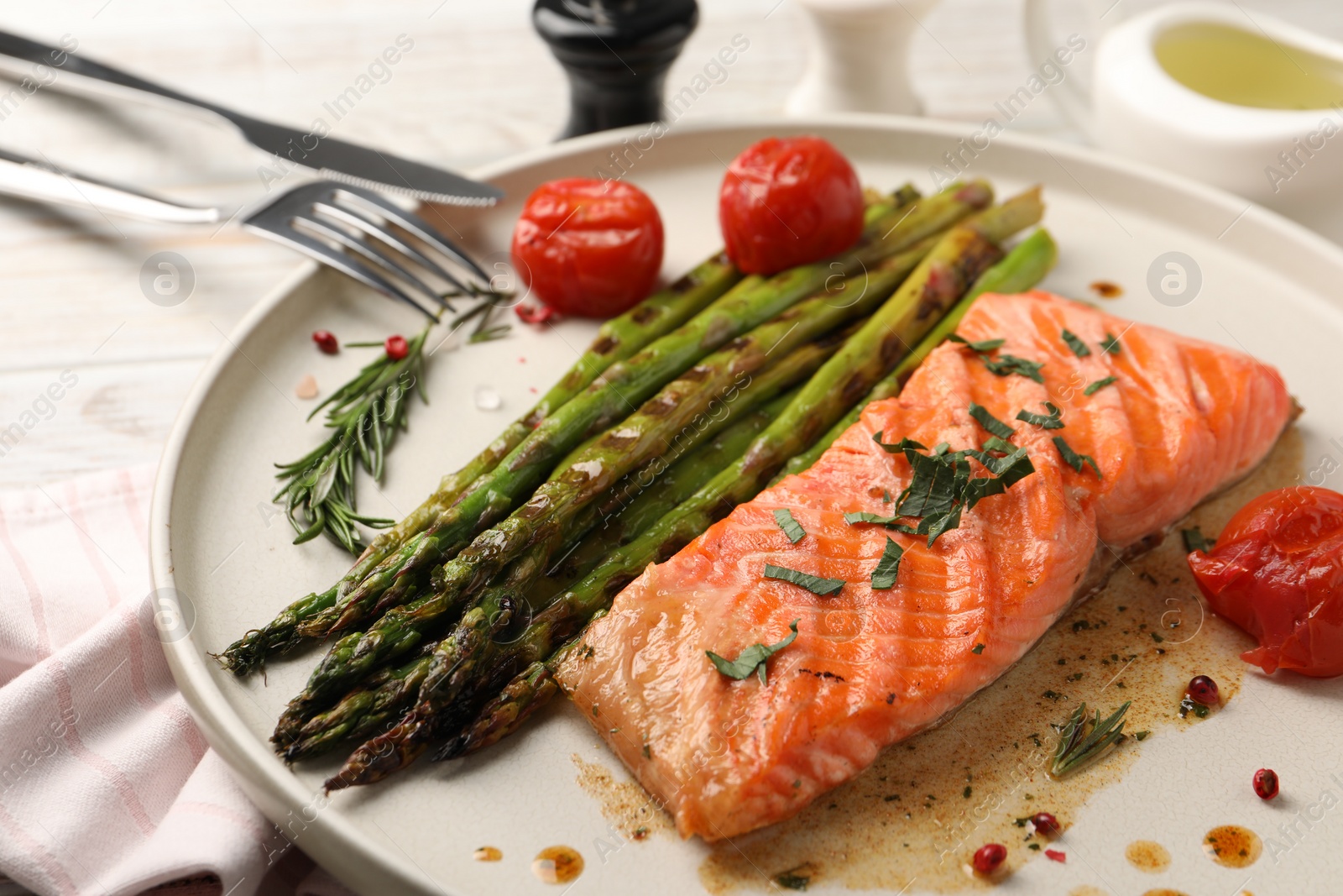 Photo of Tasty grilled salmon with tomatoes, asparagus and spices served on table, closeup