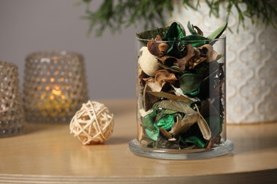 Photo of Glass jar with aromatic potpourri of dried flowers and different decor elements on wooden table indoors
