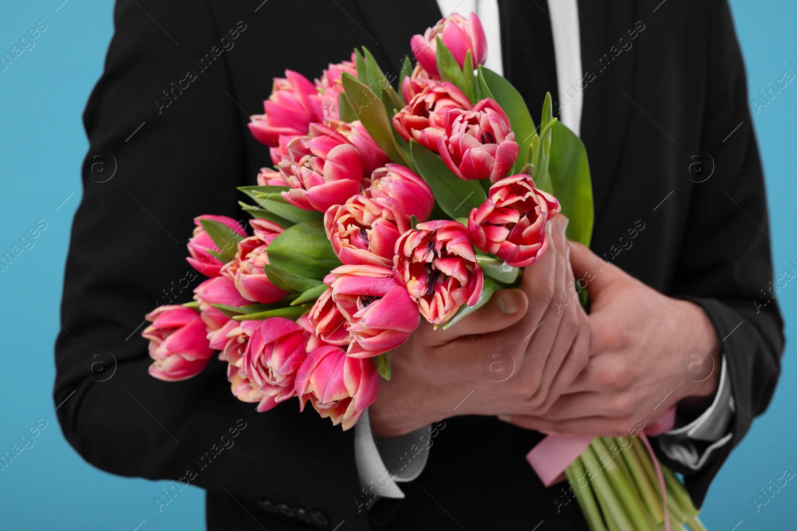 Photo of Man with beautiful bouquet on light blue background, closeup