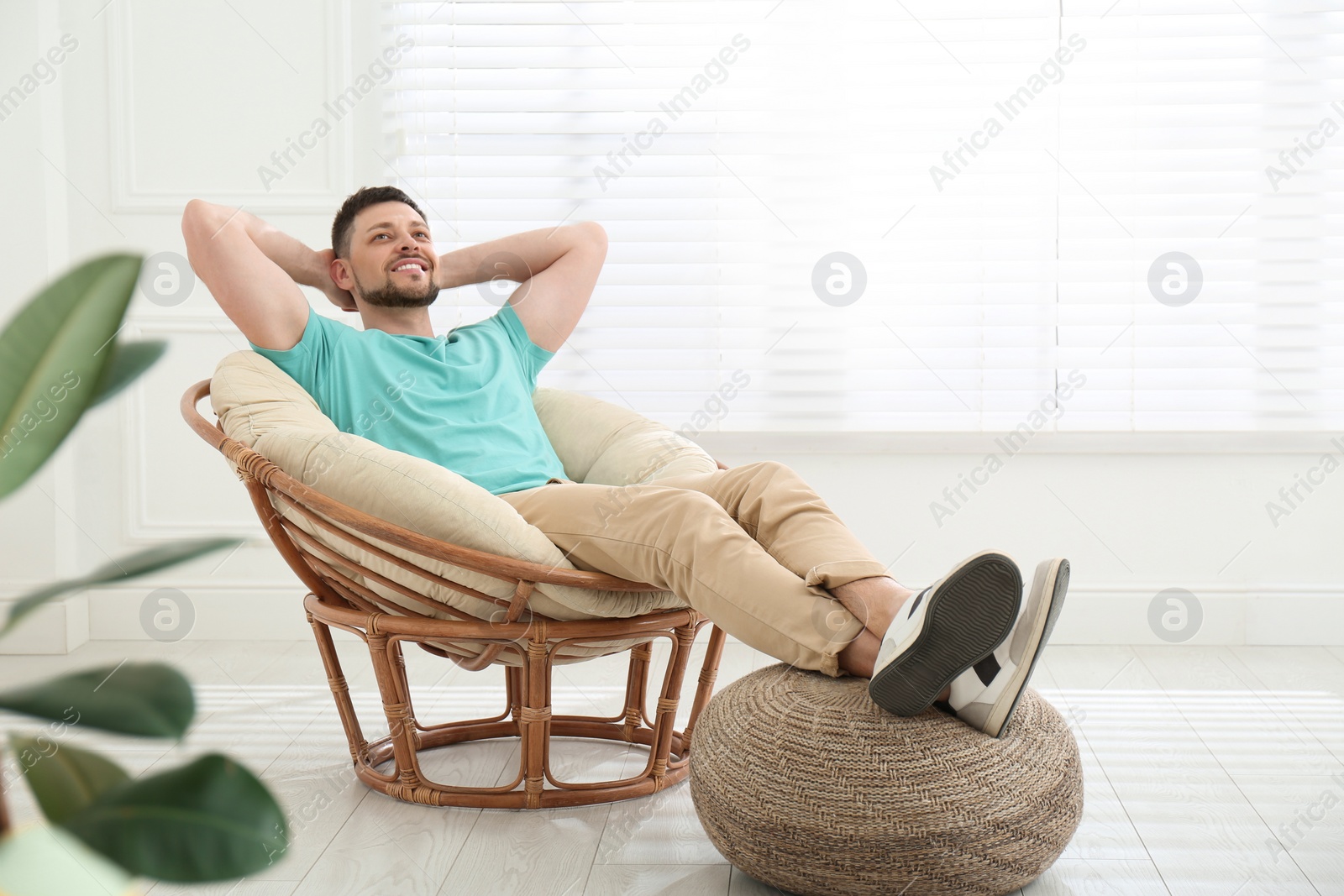 Photo of Handsome man relaxing in papasan chair at home, space for text