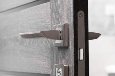 Photo of Open wooden door with metal handle, closeup