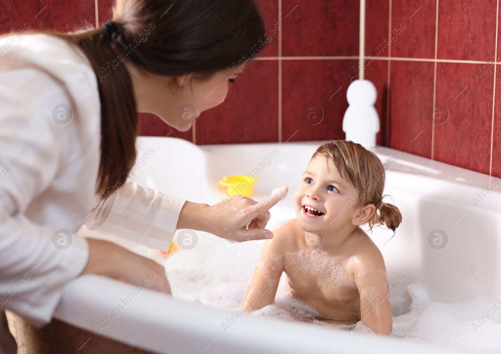 Photo of Mother playing with her little daughter in bathroom