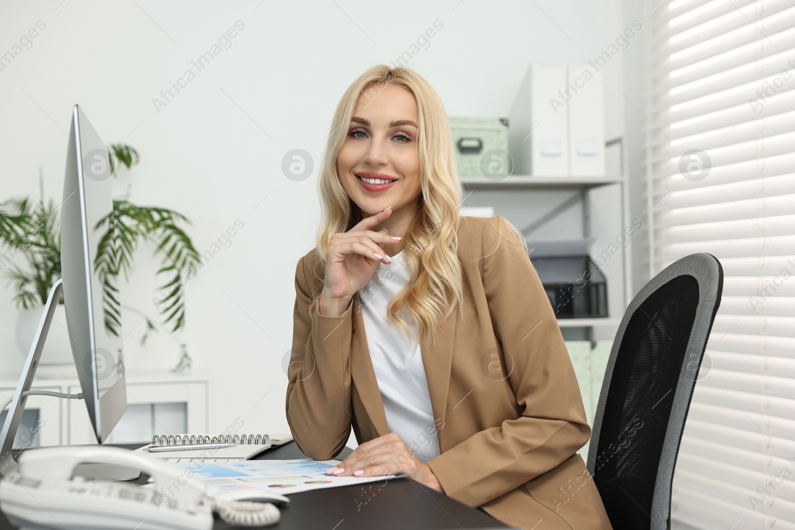 Photo of Portrait of happy secretary at table in office