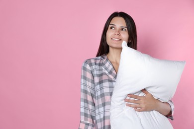 Happy young woman with soft pillow on pink background, space for text