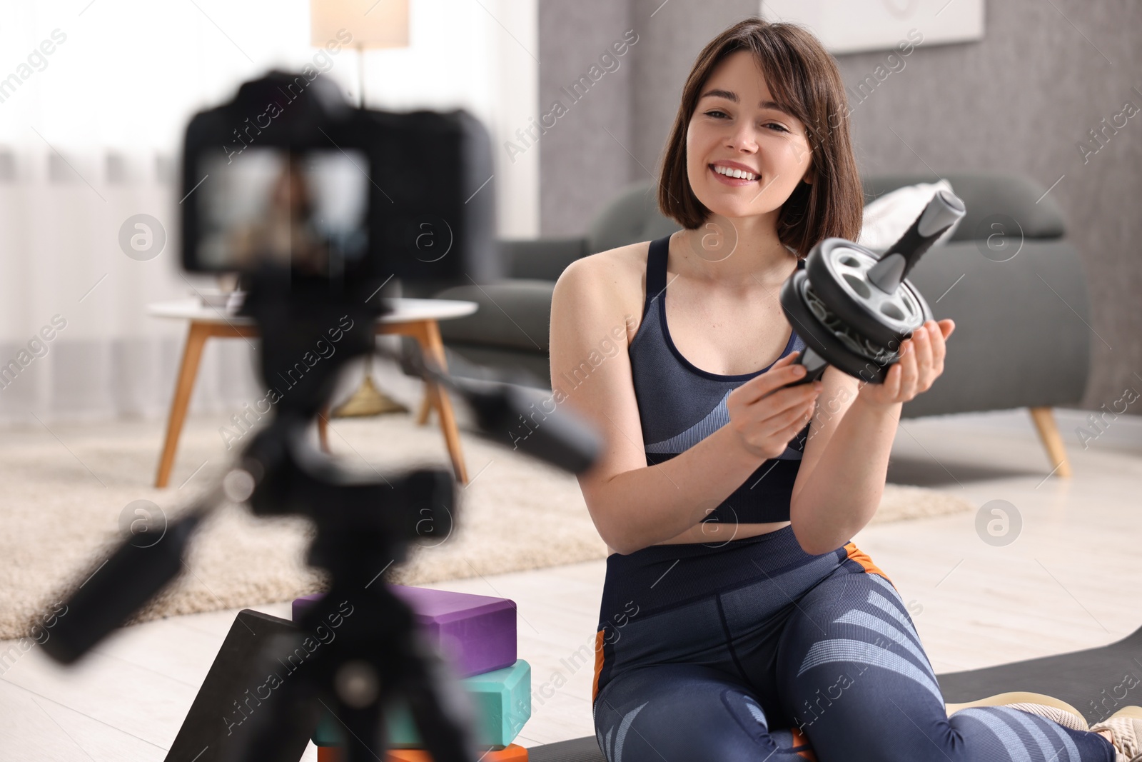 Photo of Happy sports blogger with ab roller recording fitness lesson at home