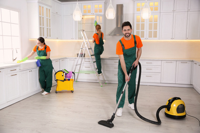 Team of professional janitors cleaning modern kitchen