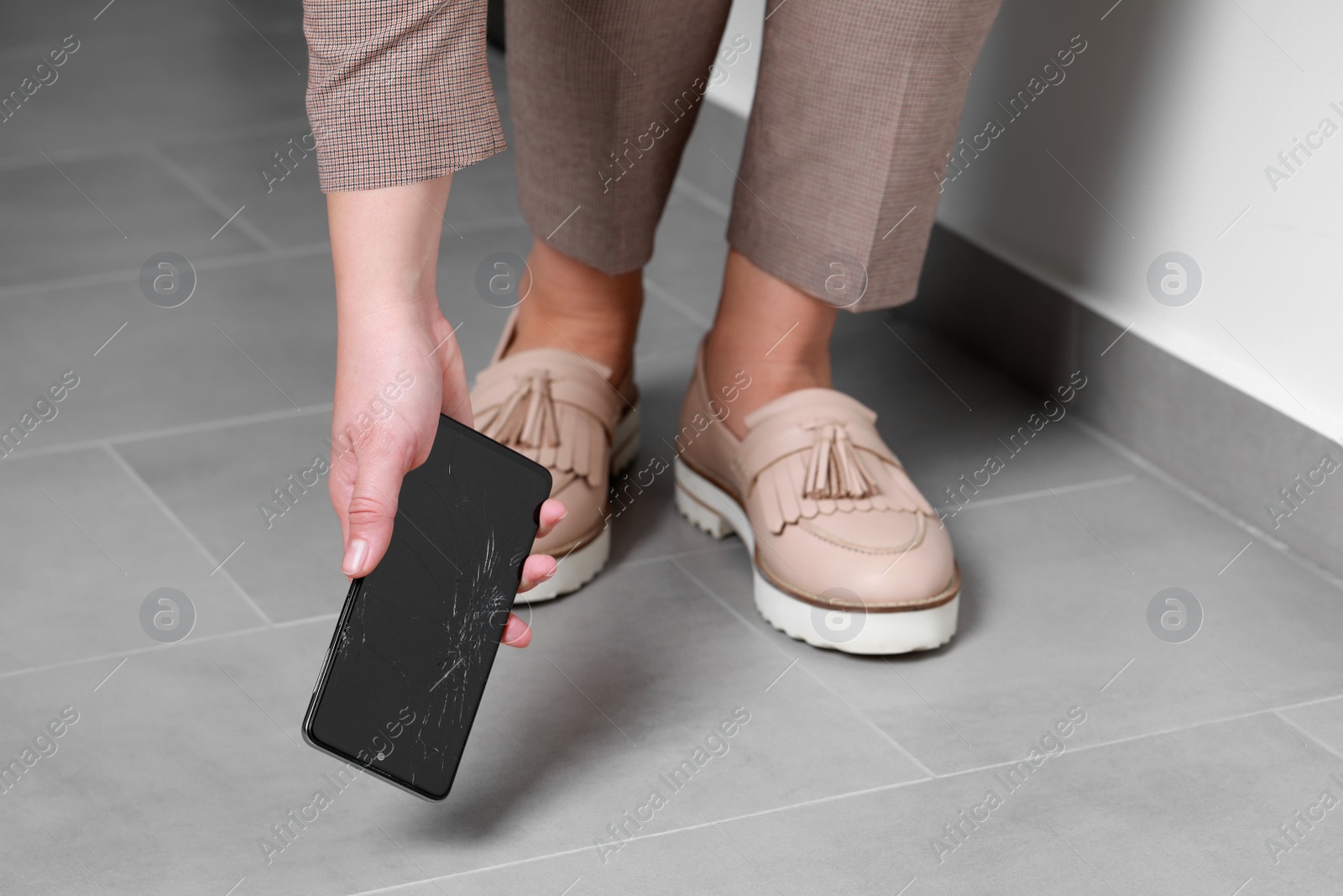 Photo of Woman taking dropped smartphone from floor, closeup. Device repairing