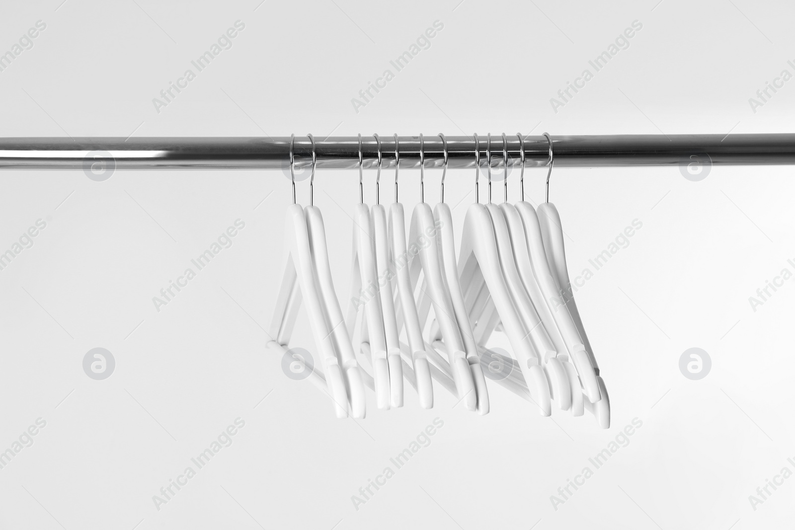 Photo of Metal rack with clothes hangers on white background