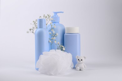 Different skin care products for baby, shower puff and toy on white background