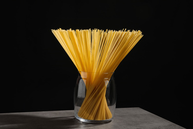 Photo of Uncooked spaghetti on grey table against black background. Italian pasta