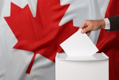 Image of Man putting his vote into ballot box against national flag of Canada, closeup. Space for text