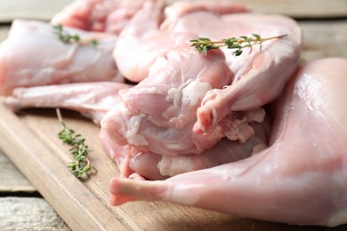 Fresh raw rabbit meat and thyme on wooden table, closeup