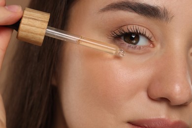 Photo of Woman applying essential oil onto face, closeup