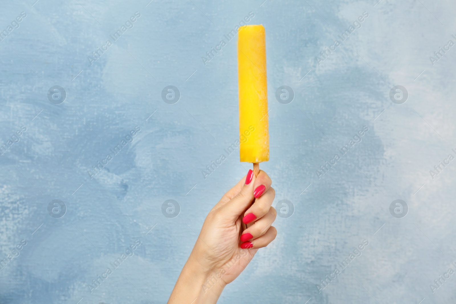 Photo of Woman holding yummy ice cream on color background. Focus on hand