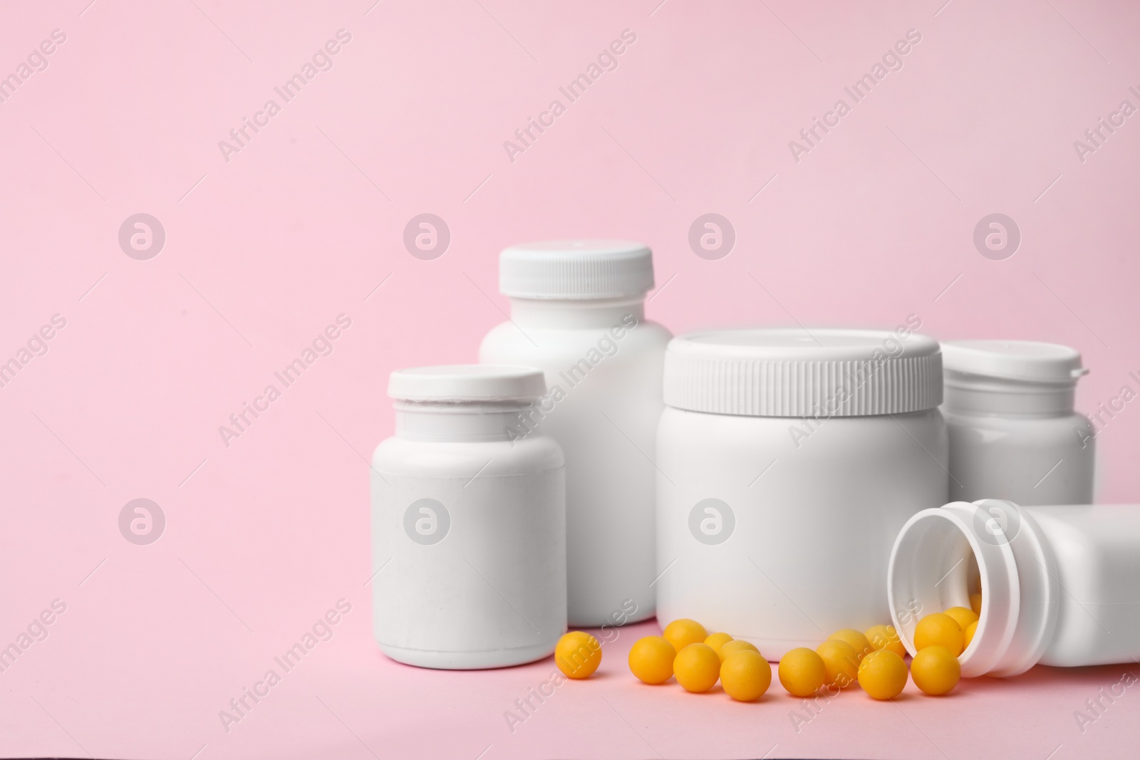 Photo of Containers and scattered pills on color background