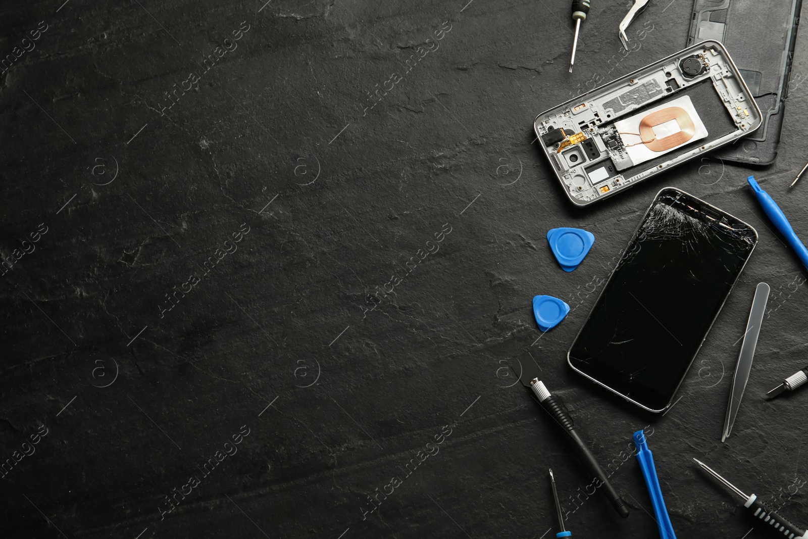 Photo of Damaged smartphone and repair tools on black background, flat lay. Space for text