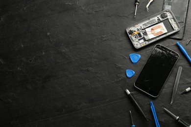 Photo of Damaged smartphone and repair tools on black background, flat lay. Space for text